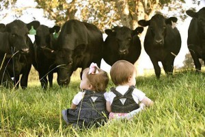 two babies in front of a herd of cows