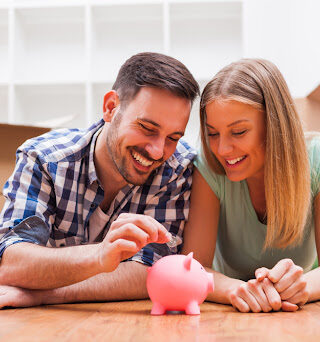 A couple putting money into a piggy bank.