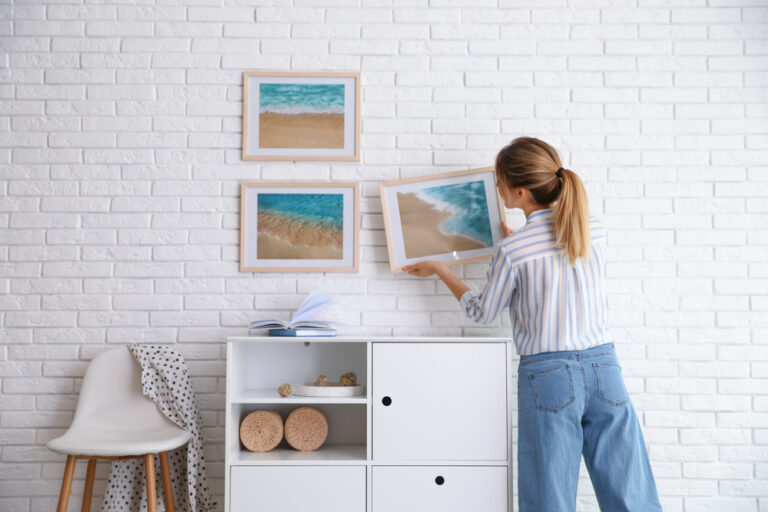 A woman takes framed photos off the wall.