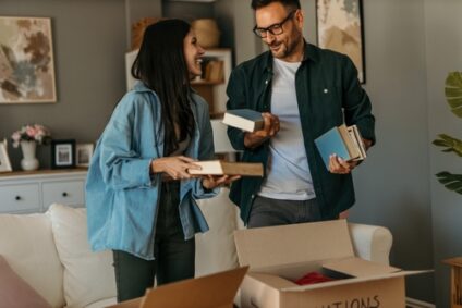 A couple sorts their books into cardboard boxes.