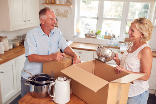 Elderly couple packing boxes in their kitchen.