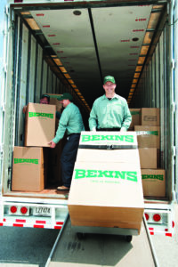 Professional movers transporting boxes out of a truck and smiling.