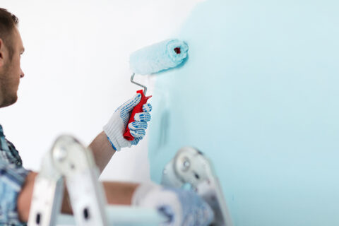 man painting a wall light blue