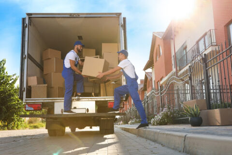 Two professional movers unload boxes from a moving truck.