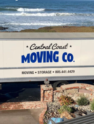 A Central coast moving company truck parked in front of a house, with crashing waves behind it.