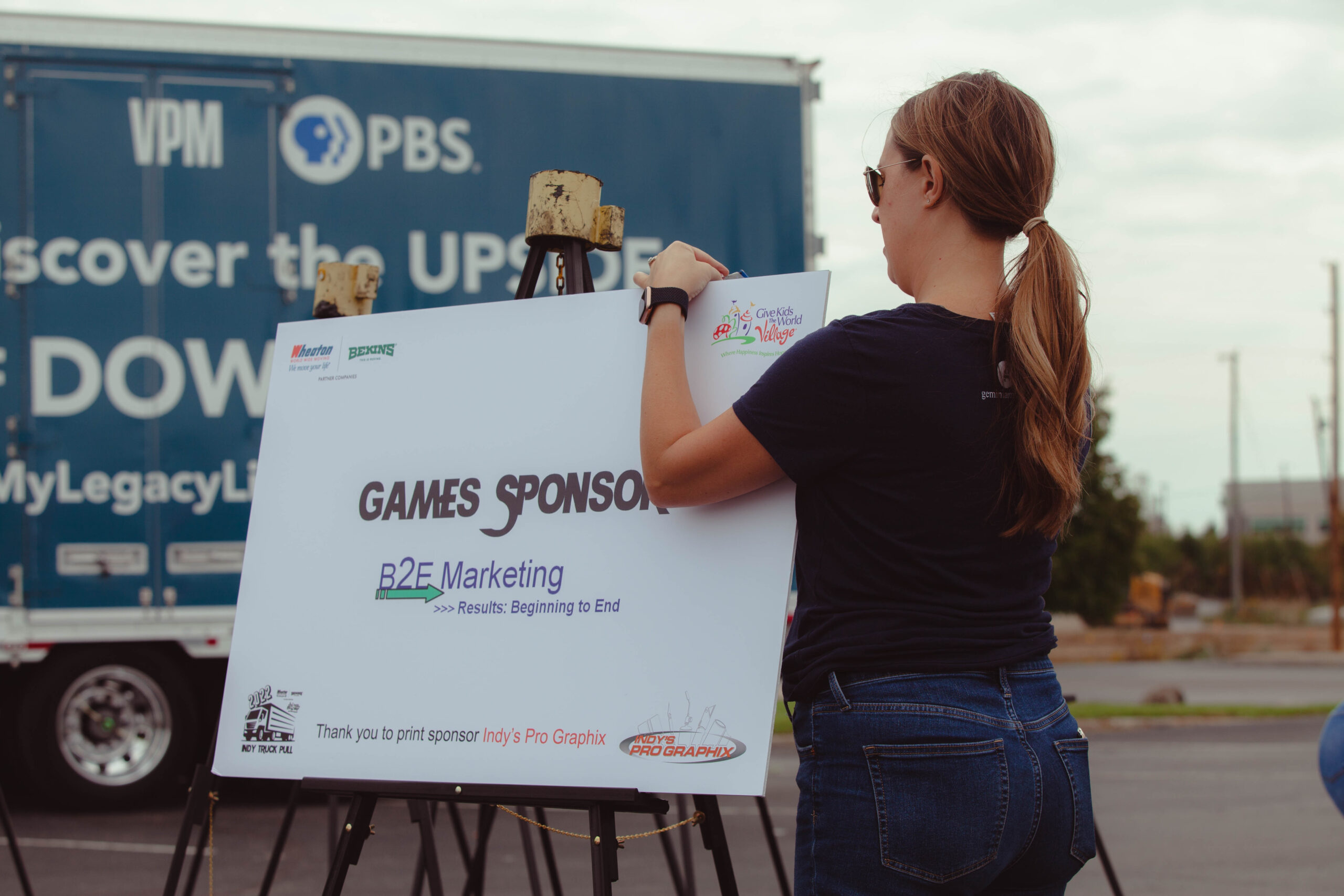Volunteer sets up sponsor signs at truck pull fundraiser