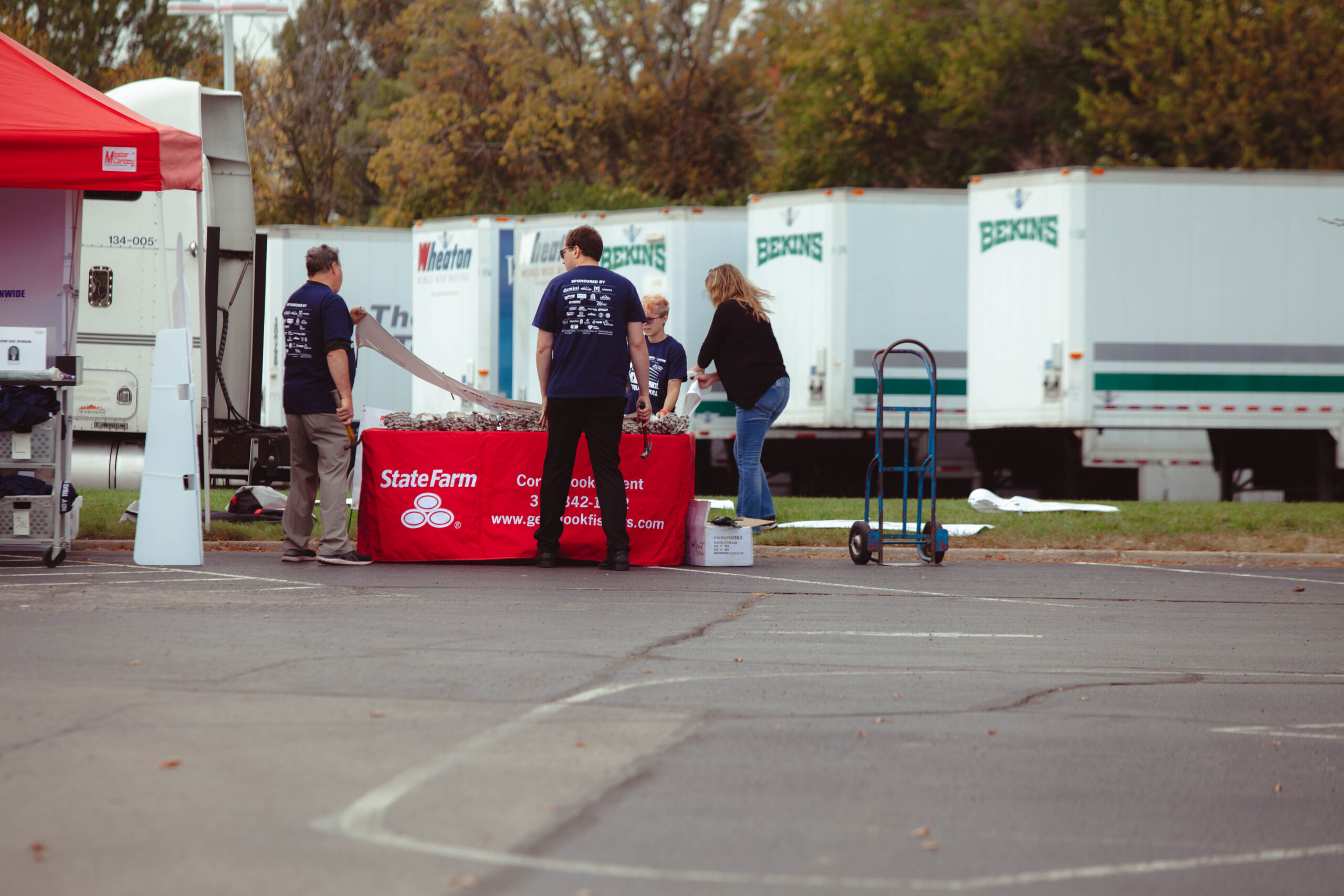 Volunteers set up sponsor table in front of Bekins trailers at truck pull fundraiser