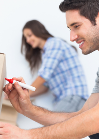 couple labeling cardboard moving boxes