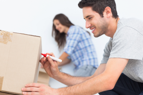 couple labeling cardboard moving boxes