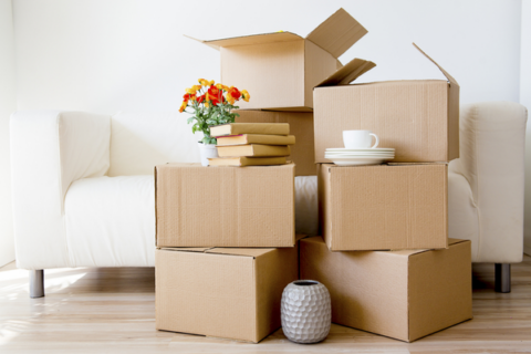 moving boxes and items stacked in front of couch