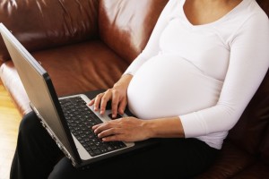pregnant women typing on a laptop