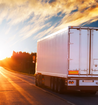 A white semi truck driving in the right lane during sunset