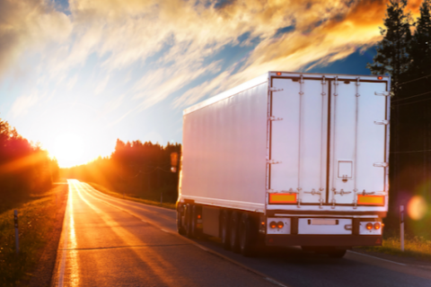 A white semi truck driving in the right lane during sunset