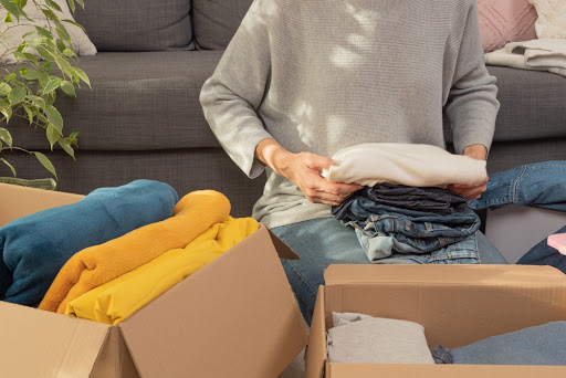 Woman sorting clothes into cardboard boxes.