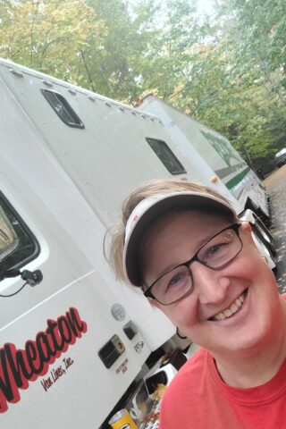 Woman taking a selfie in front of Wheaton's moving van