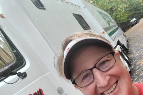 Woman taking a selfie in front of Wheaton's moving van