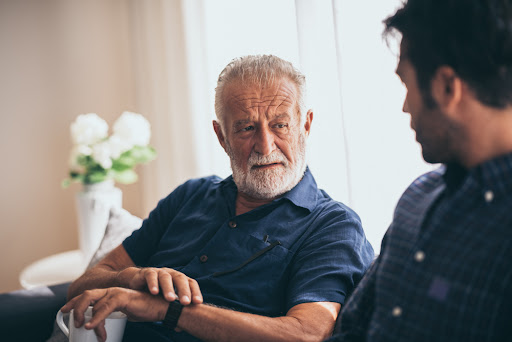 Elderly father and son  talking on the couch.