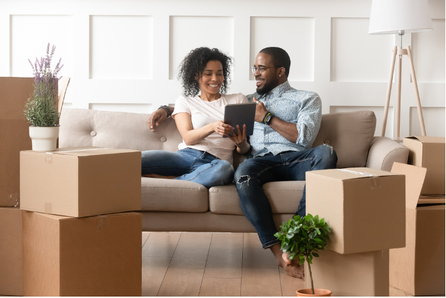 couple sitting on a couch surrounded in moving boxes