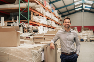 Smiling person leans against moving supplies.