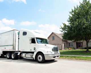 A Bekins moving truck parked outside of a residential home.