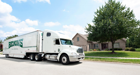 A Bekins moving truck parked outside of a residential home.