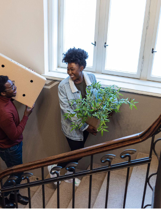 Couple moving belongings into new apartment up the stairs