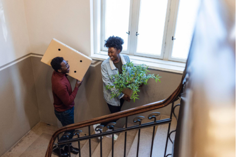 Couple moving belongings into new apartment up the stairs