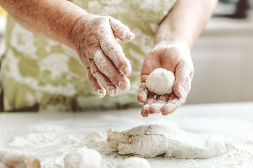 Person with floured hands forming small balls of dough.