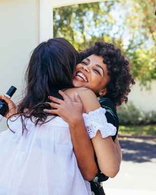 Woman greeting couple and hugging woman in entryway of new house