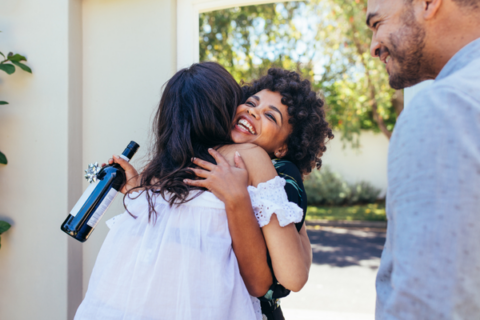 Woman greeting couple and hugging woman in entryway of new house