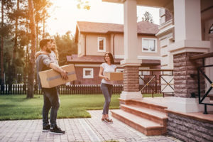 Couple carries moving boxes into new home.