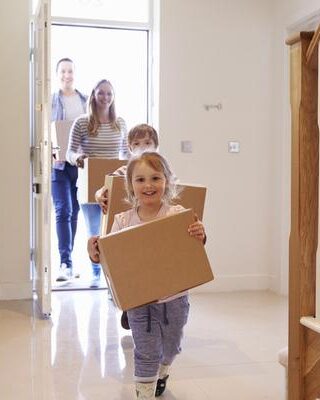 A family moving into their new home, every person with a box to carry