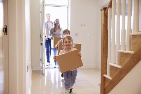 A family moving into their new home, every person with a box to carry
