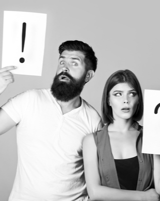 An exasperated couple holding up exclamation point and question mark signs