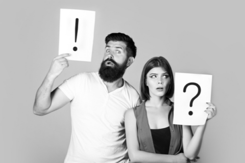 An exasperated couple holding up exclamation point and question mark signs