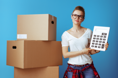 women with large calculator standing next to moving boxes