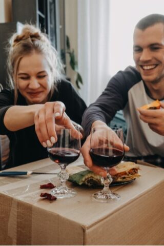 Couple unpacking and eating on a cardboard box after moving