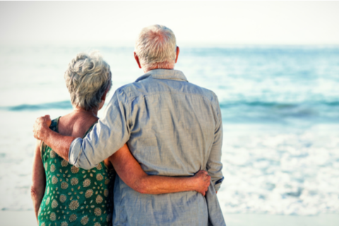 Older couple embracing in front of ocean