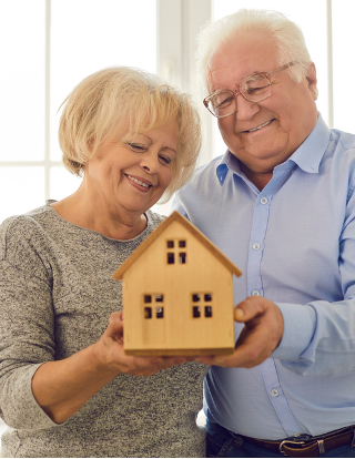 older couple holding small model home