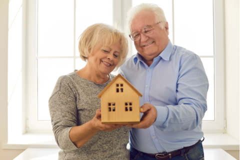older couple holding small model home