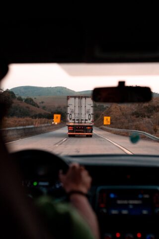 Closeup of a person driving behind a semi truck.