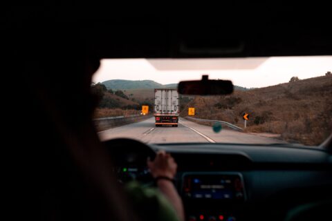 Closeup of a person driving behind a semi truck.