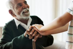 Senior man holds hand of younger person.