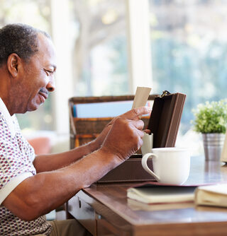 A senior man reads an old letter taken from a wooden box.