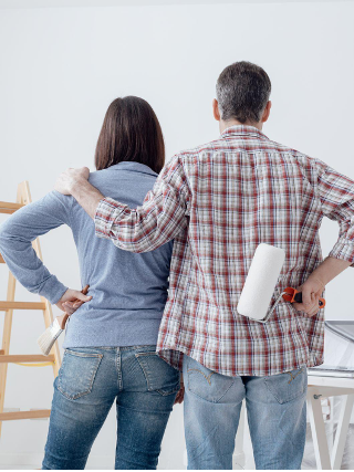 Couple staring at their freshly painted room, back view: home renovation