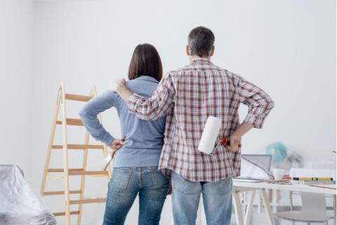 Couple staring at their freshly painted room, back view: home renovation