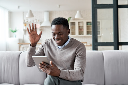 Happy african american man video calling online holding digital tablet. Black guy waving hand talking by virtual meeting with family via social distance conference videocall in remote chat at home.