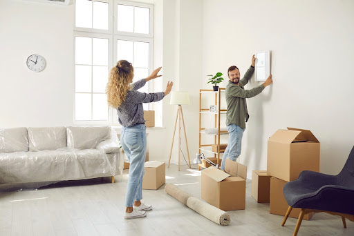 A couple hanging a picture on a wall.