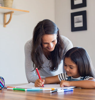 A mother and her child coloring at a table.