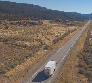 A moving truck drives on a long stretch of highway.